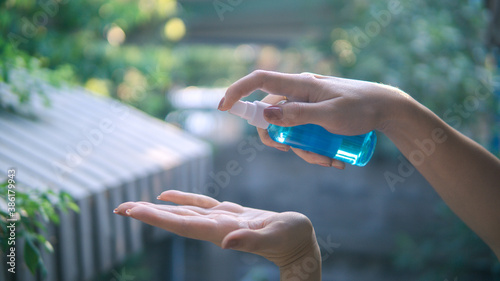 Close up view of woman using small portable antibacterial hand sanitizer on hands.