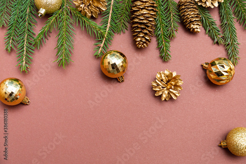 Golden Christmas balls, pine cones and fir branches on a brown background space for text. Christmas and New Years composition