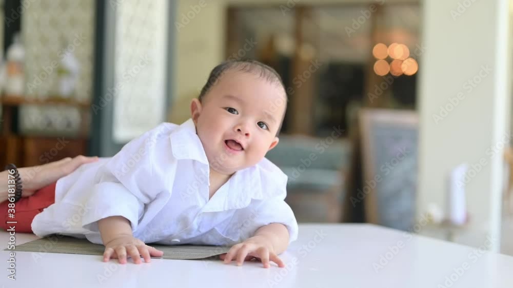 Smiling crawling asian baby boy on floor at home with white shirt