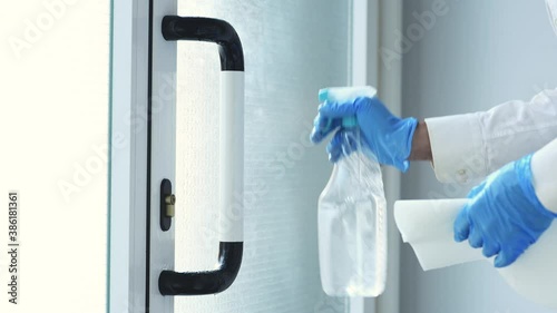 hands with nitrile gloves and a hydroalcoholic solution spray clean the door handle to prevent coronavirus with disposable paper
