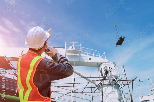 shipyard repairing and crane during installed scaffolding in floating  walkie- talkie or portable radio transceiver for communication in hand holding control worker order for maintenance 