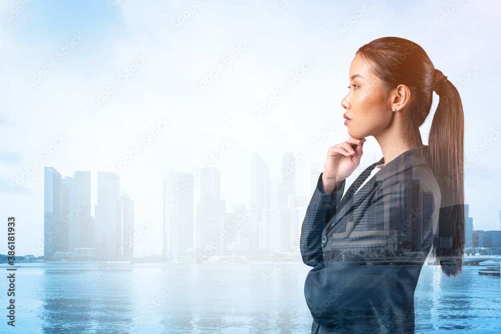 Attractive young Asian business woman in suit with hand on chin thinking how to succeed, new career opportunities, MBA. Singapore on background. Double exposure.