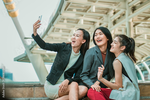 Businesswoman friends selfie with smartphone and pointing at screen surprised