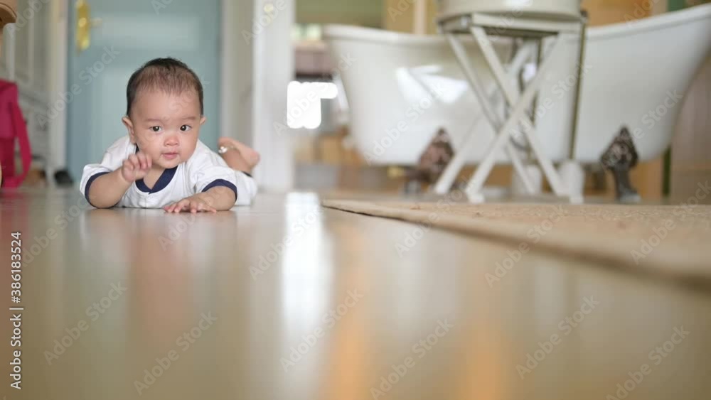 Smiling crawling asian baby boy on floor at home with white shirt