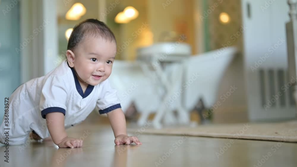 Smiling crawling asian baby boy on floor at home with white shirt Smiling crawling asian baby boy on floor at home with white shirt