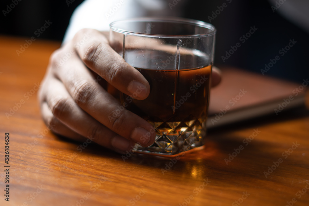 holding beverage drink in hand on table with dark moody lighting holding beverage drink in hand on table with dark moody lighting