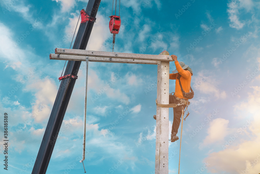 Worker on the height wear safety harness, Electric lineman repairman worker at climbing work on electric post power pole on blue sky. Worker on the height wear safety harness, Electric lineman repairman worker at climbing work on electric post power pole on blue sky.