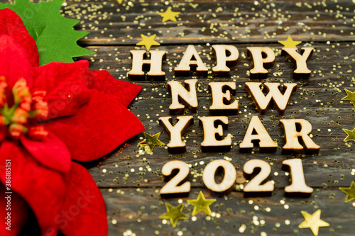 Happy New year 2021 celebration. Wooden text and poinsettia on wooden background. Flat lay.