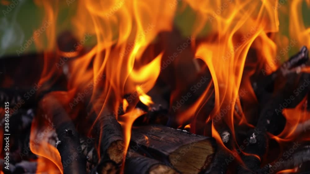 Wooden logs in bright flame. Wood burning in fire. Orange flame over the smoldering logs. Close-up. Slow motion. Wooden logs in bright flame. Wood burning in fire. Orange flame over the smoldering logs. Close-up. Slow motion.