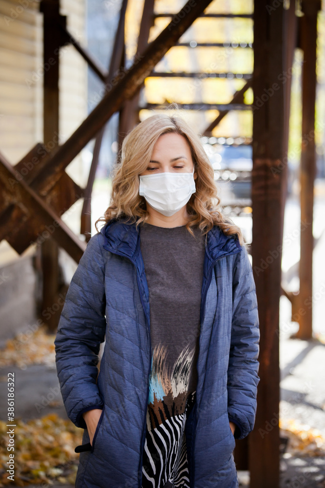 white woman blonde in a medical mask walks down the street alone white woman blonde in a medical mask walks down the street alone