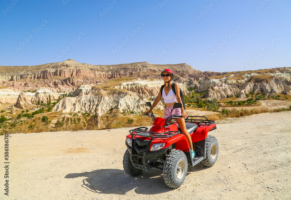 Young woman riding red quad bike at the desert valley in Cappadocia Turkey 2020. Red atv quad at the valley. Young woman riding red quad bike at the desert valley in Cappadocia Turkey 2020. Red atv quad at the valley.