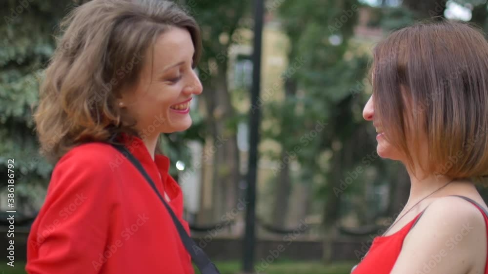 Happy meeting of two female friends hugging and smiling at the street on trees background, friendship concept Happy meeting of two female friends hugging and smiling at the street on trees background, friendship concept