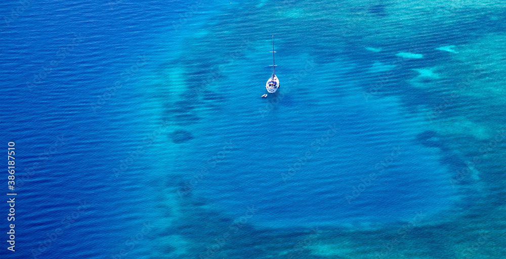 White yacht floating above a coral reef in beautiful bay. Aerial view.