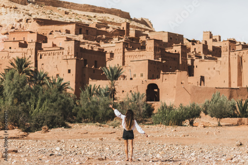 Woman enjoying popular landmark ksar Ait-Ben-Haddou. View from behind. Travel in Morocco, Ouarzazate. Wanderlust concept.