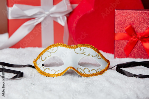 Carnival mask on a snow near gift boxes