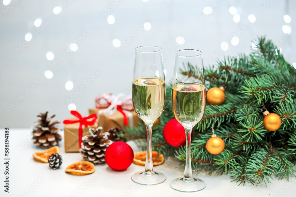 Two glasses of champagne composition with Christmas and new year decorations on a blurry background of burning garlands Two glasses of champagne composition with Christmas and new year decorations on a blurry background of burning garlands