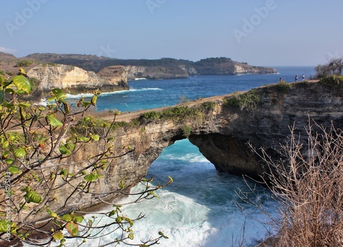 Scenic natural arch with plants in foreground at Broken Beach, Nusa Penida, Indonesia