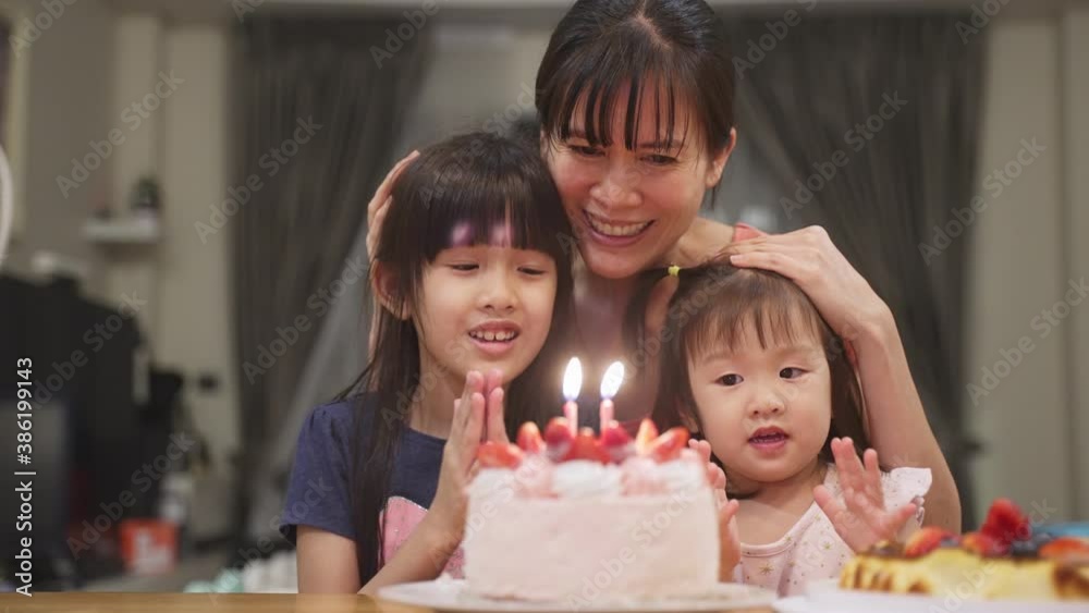 Asian young mother and daughters blowing out the candles birthday cake Asian young mother and daughters blowing out the candles birthday cake