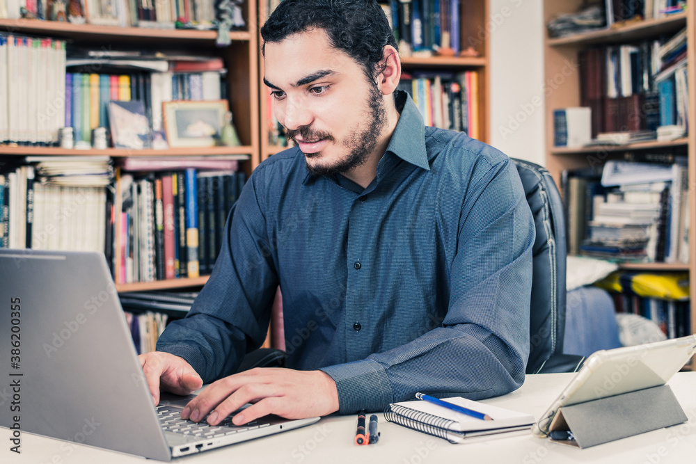 Young entrepreneur working from home, writing on his laptop Young entrepreneur working from home, writing on his laptop