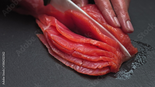 Chef takes out bones from the salmon fillet, cutting fish on slices for cooking sushi in 4k resolution in slow motion