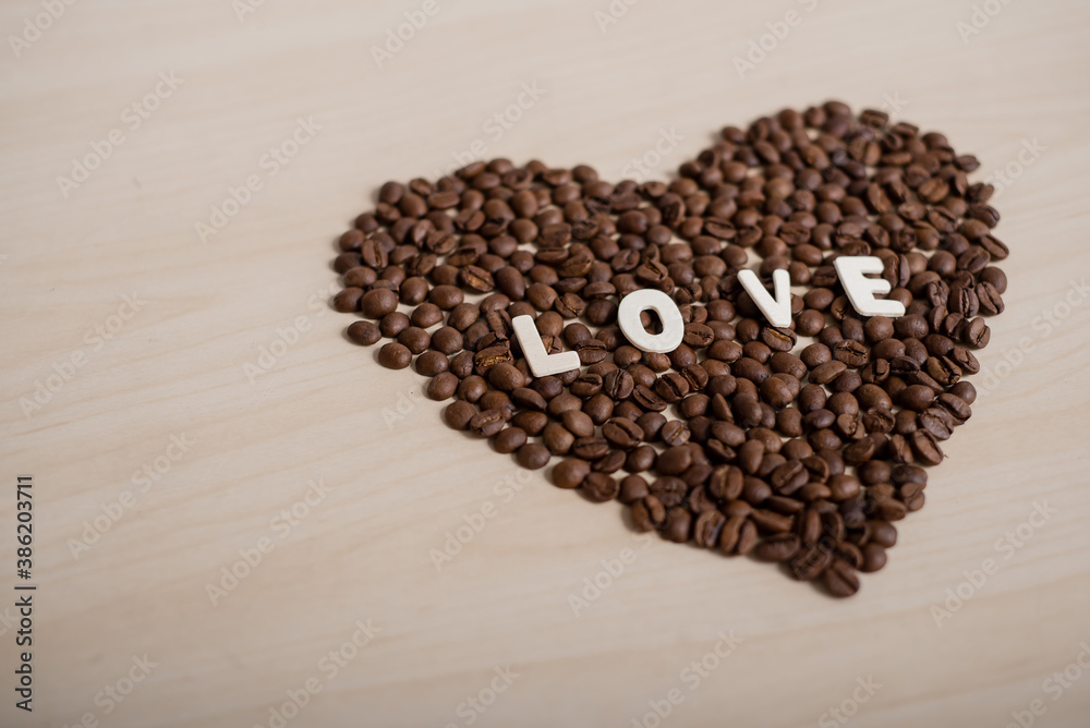 Coffee beans in the shape of a heart and the inscription love on a wooden table Coffee beans in the shape of a heart and the inscription love on a wooden table