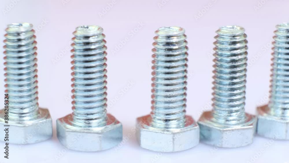 Moving row of galvanized metallic screws close-up. Stainless steel bolts isolated on white background. Industrial concept. Moving row of galvanized metallic screws close-up. Stainless steel bolts isolated on white background. Industrial concept.