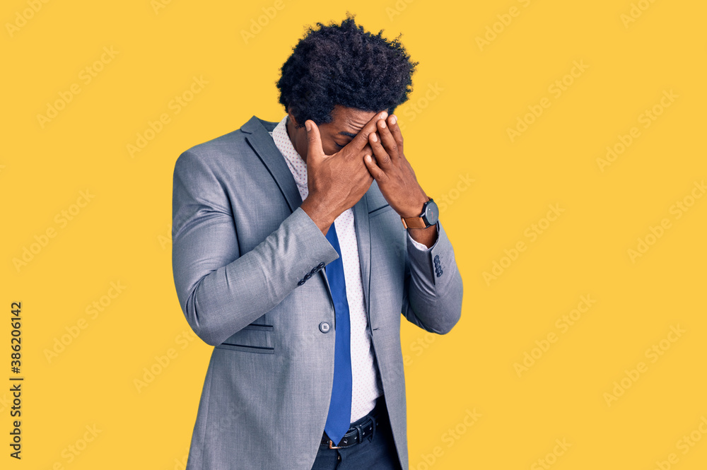 Handsome african american man with afro hair wearing business jacket with sad expression covering face with hands while crying. depression concept. Handsome african american man with afro hair wearing business jacket with sad expression covering face with hands while crying. depression concept.