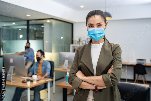 Asian young businesswoman wearing face mask, standing in the office.