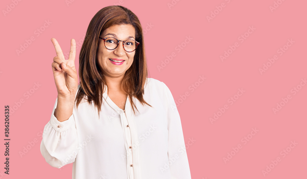 Middle age latin woman wearing casual clothes and glasses showing and pointing up with fingers number two while smiling confident and happy. Middle age latin woman wearing casual clothes and glasses showing and pointing up with fingers number two while smiling confident and happy.
