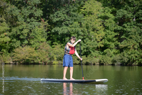 Boy standing up on a paddleboard on calm lake