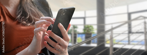 Fotografía Young businesswoman, teenager girl business woman using mobile smartphone in a office or school building, texting or chatting a messages