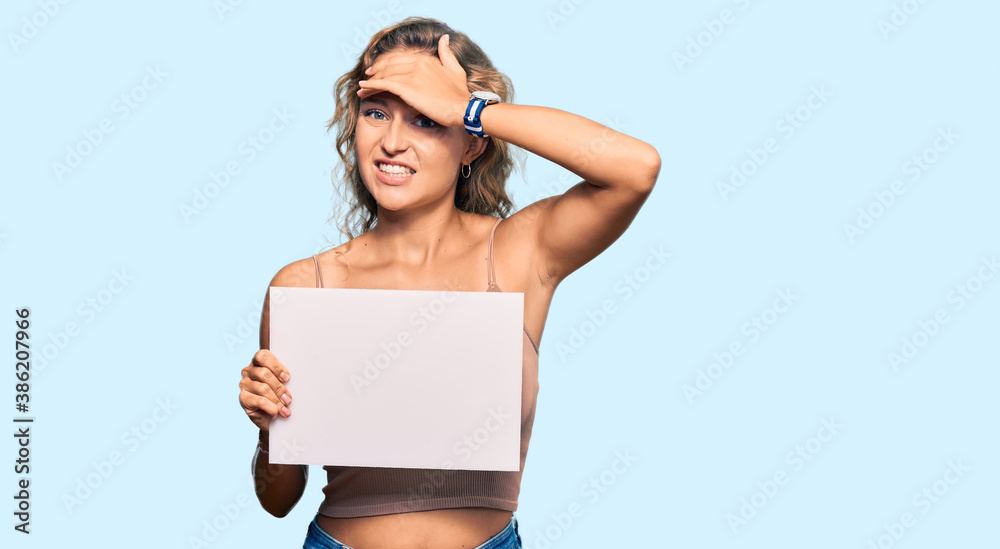 Beautiful caucasian woman holding blank empty banner stressed and frustrated with hand on head, surprised and angry face Beautiful caucasian woman holding blank empty banner stressed and frustrated with hand on head, surprised and angry face
