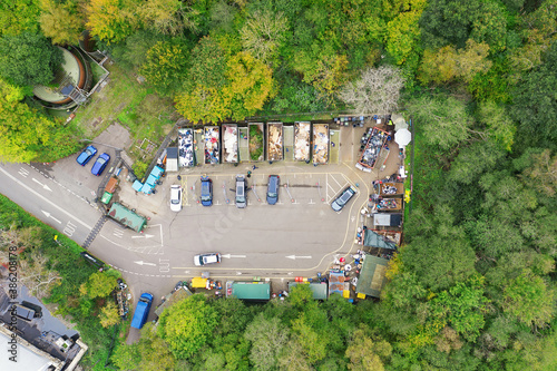 Aerial view of people in cars taking garbage to the waste recycling centre which is surrounded by green trees. Various containers with different rubbish, for the environment. With Social Distancing.