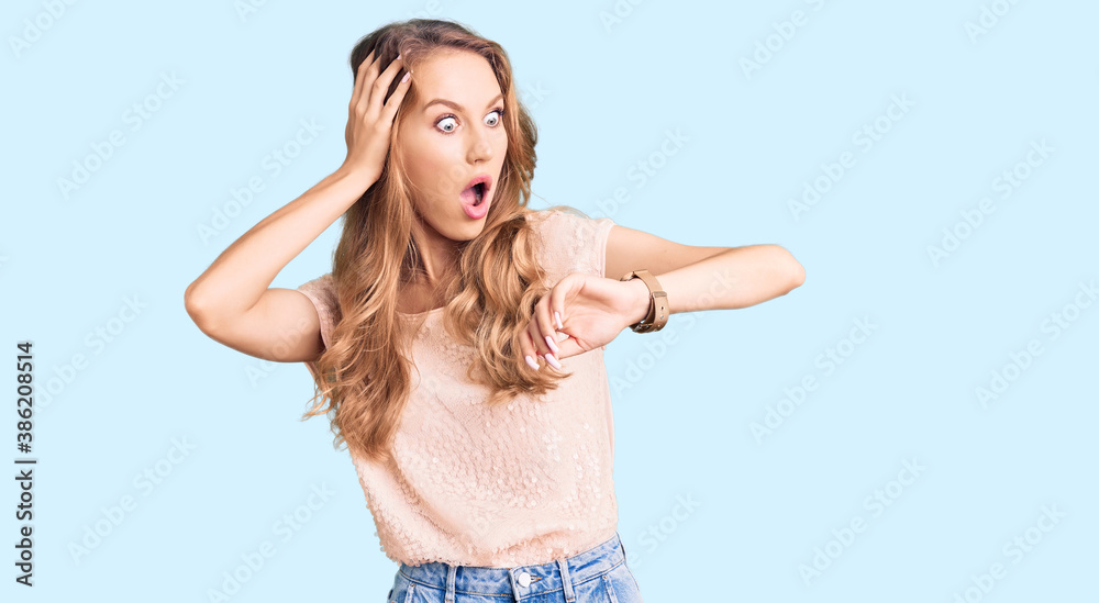 Young beautiful caucasian woman with blond hair wearing casual clothes looking at the watch time worried, afraid of getting late Young beautiful caucasian woman with blond hair wearing casual clothes looking at the watch time worried, afraid of getting late