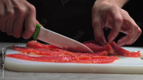 male chef cuts fillet of fresh salmon into large chunks. Cooking fish in kitchen. Preparation of ingredients by chef to prepare dish. Cooking in the restaurant kitchen. Food ingredients for gourmets