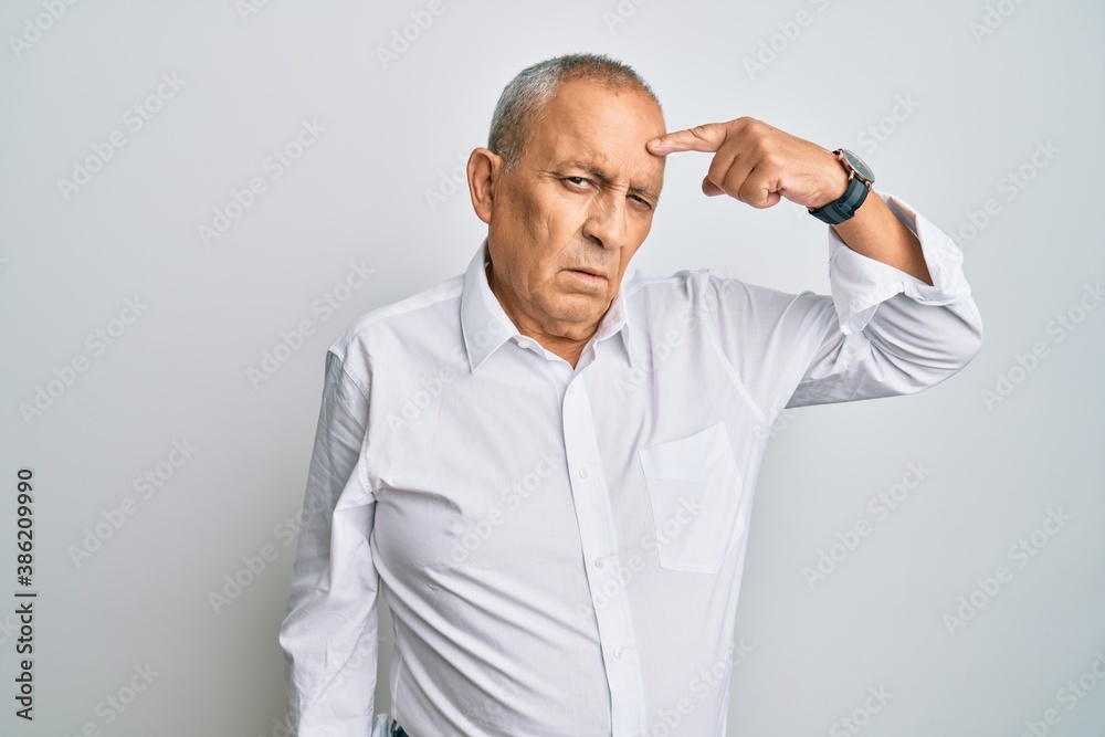 Handsome senior man wearing casual white shirt pointing unhappy to pimple on forehead, ugly infection of blackhead. acne and skin problem Handsome senior man wearing casual white shirt pointing unhappy to pimple on forehead, ugly infection of blackhead. acne and skin problem