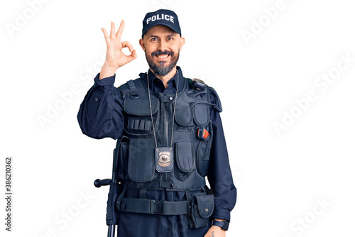 Young handsome man wearing police uniform smiling positive doing ok sign with hand and fingers. successful expression.