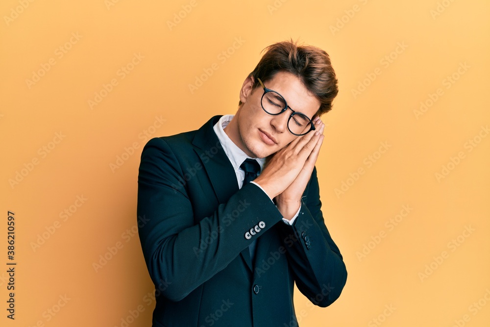 Handsome caucasian man wearing business suit and tie sleeping tired dreaming and posing with hands together while smiling with closed eyes. Handsome caucasian man wearing business suit and tie sleeping tired dreaming and posing with hands together while smiling with closed eyes.