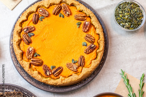 Pumpkin pie decorated with pecans on a served table for an autumn party food