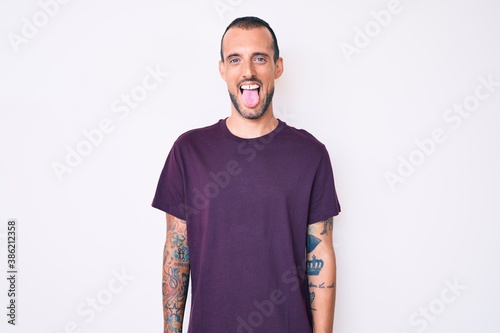 Wallpaper Mural Young handsome man with tattoo wearing casual clothes sticking tongue out happy with funny expression. emotion concept. Torontodigital.ca