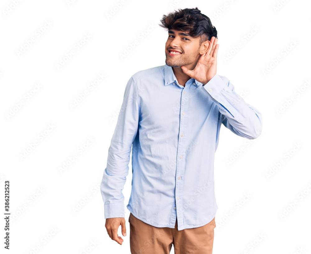 Young hispanic man wearing casual shirt smiling with hand over ear listening an hearing to rumor or gossip. deafness concept.