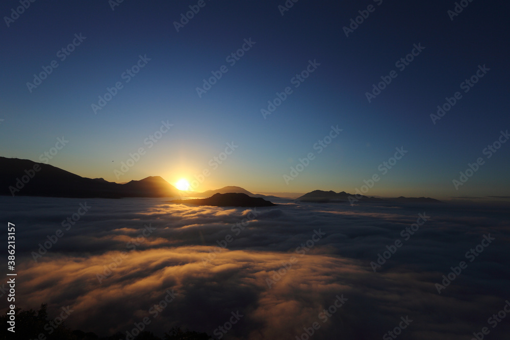 new day - the sun at dawn with fog and backlit mountains