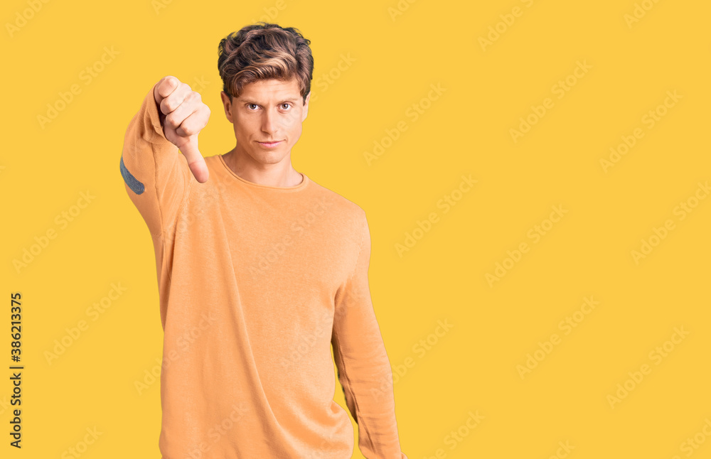 Young handsome man wearing casual clothes looking unhappy and angry showing rejection and negative with thumbs down gesture. bad expression. Young handsome man wearing casual clothes looking unhappy and angry showing rejection and negative with thumbs down gesture. bad expression.