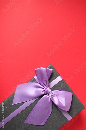 new year's Christmas holiday mother's day Valentine's day birthday anniversary gift box black with purple purple fuchsia colors with a bow on a red background copy space © Кристина Шоба