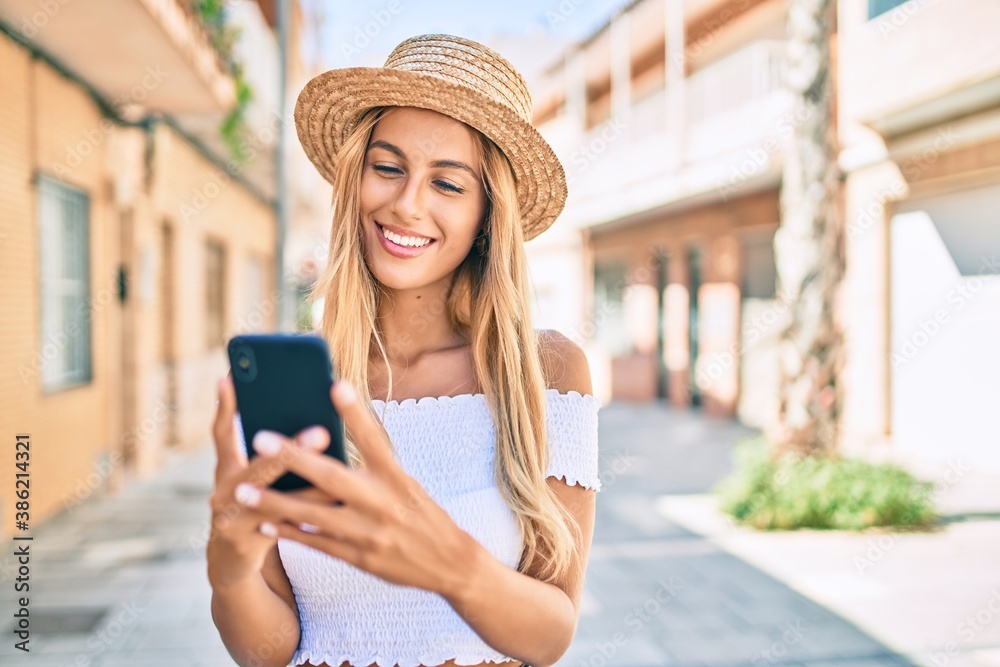 Young blonde tourist girl smiling happy using smartphone at the city.