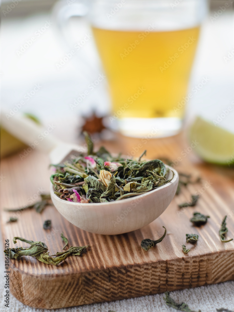green tea leaves in wooden spoon with lime slices and mug of brewed tea on wooden background green tea leaves in wooden spoon with lime slices and mug of brewed tea on wooden background