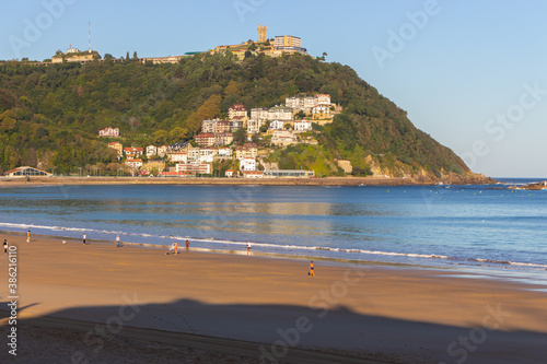 San Sebastian, Spain - 10/11/2019: Seashore with unknown people. Wide aerial beach in morning sunlight. People walking on coast of Biscayne bay. Healthy and relax lifestyle. Scenic seascape in morning