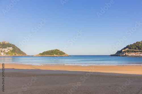 San Sebastian, Spain - 10/11/2019: Seashore with unknown people. Wide aerial beach in morning sunlight. People walking on coast of Biscayne bay. Healthy and relax lifestyle. Scenic seascape in morning
