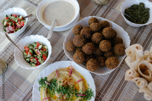 A table spread of middle-eastern dishes like hummus and falafel and salad