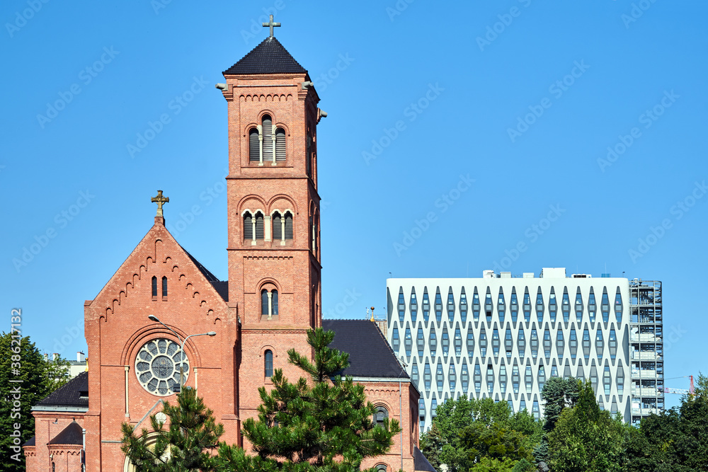 A historic Catholic church with a bell tower and a facade of a modern office building